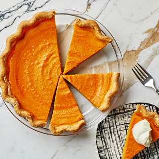 Sweet potato pie sliced sitting on marble surface.